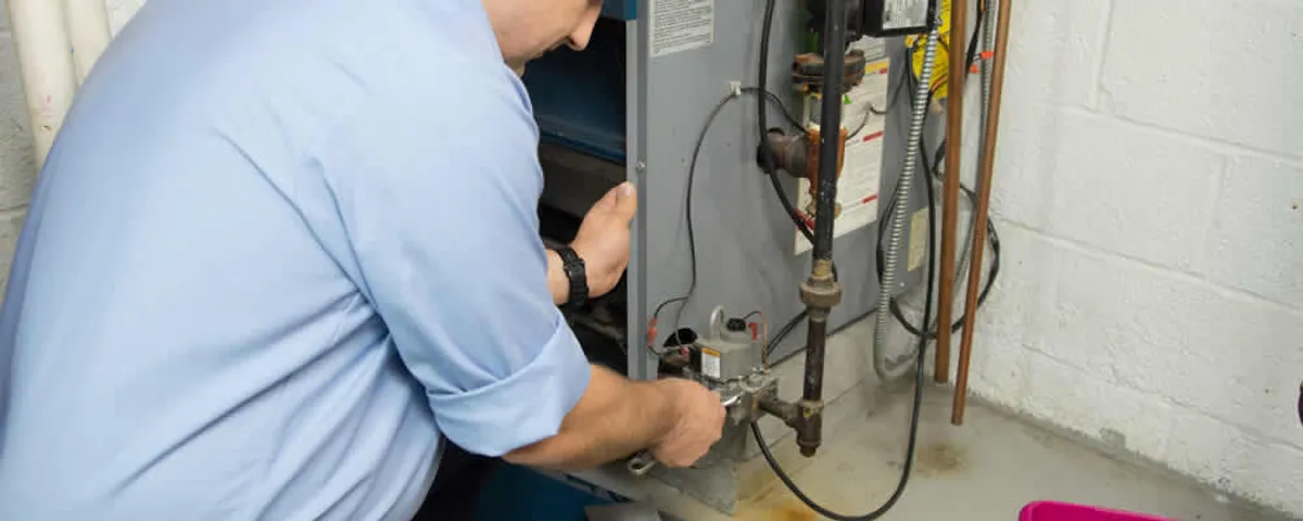 Furnace repair technician inspecting and servicing a home heating system in Newton, MA