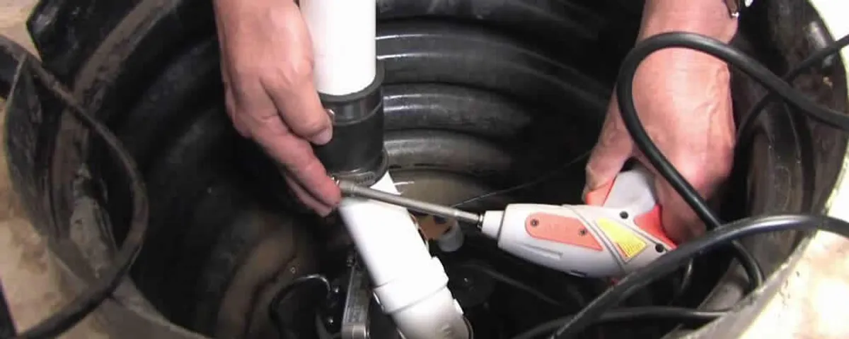 Sump pump installation technician connecting PVC discharge piping in Newton, MA