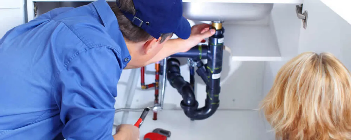 Plumber repairing under-sink drain pipes and fittings in Newton, MA
